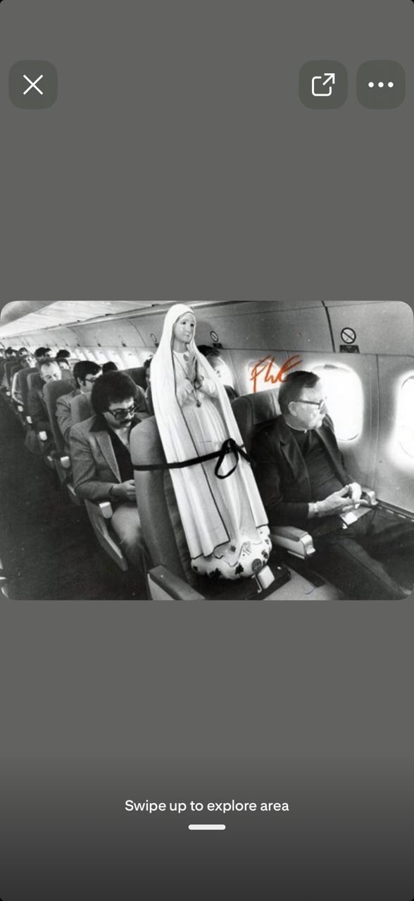 Black and white photograph of a Mary statue in an airplane cabin